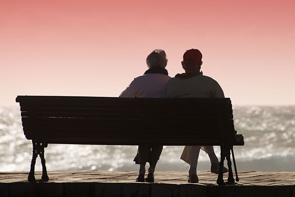 Old couple sitting on a bench. Lives well-lived.