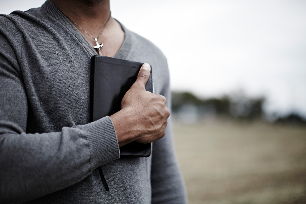 Man holding Bible close to his chest