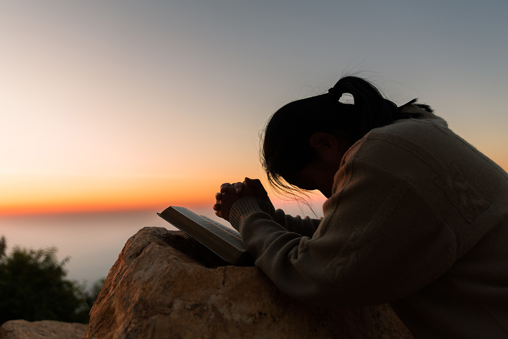 Woman praying while reading the Bible