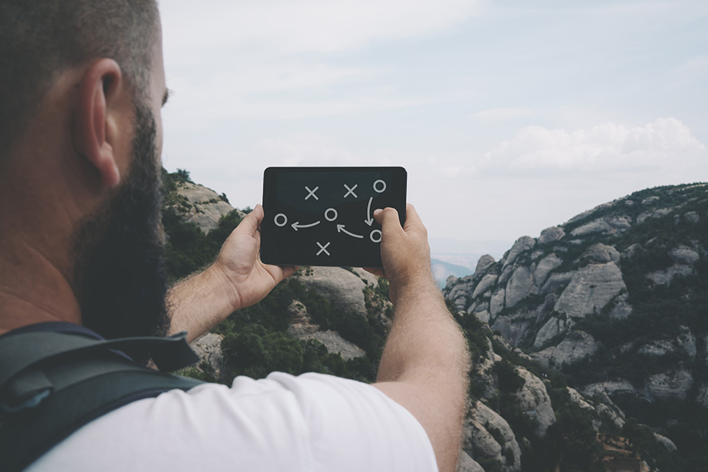 Man with phone showing a diagram of football play out in nature