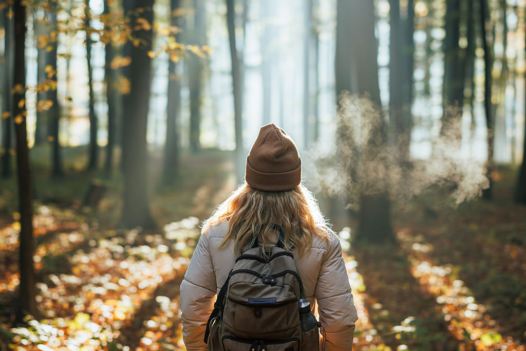 Woman in forest with fall leaves reflecting on God's goodness