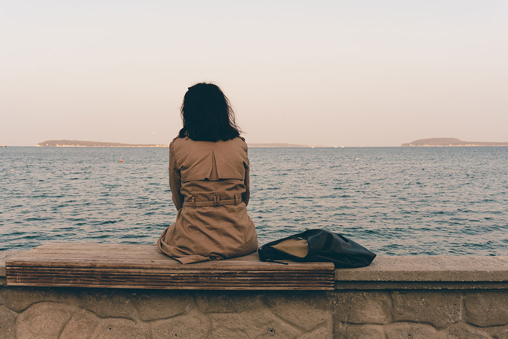 Woman grieving sitting by a lake.