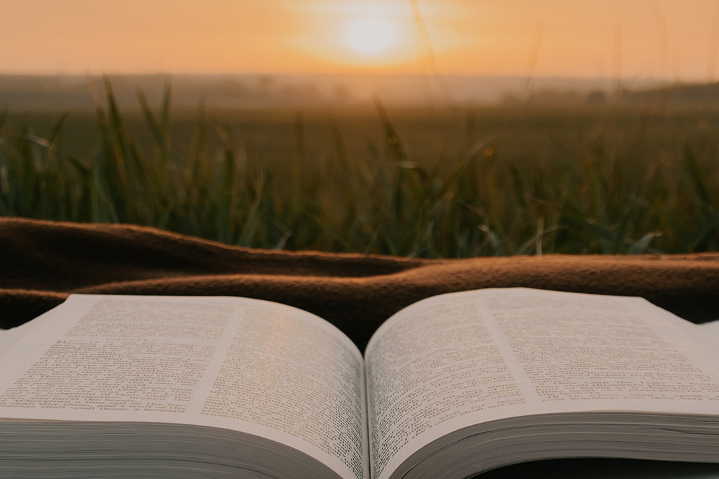 An open Bible with the sunrising in the distance