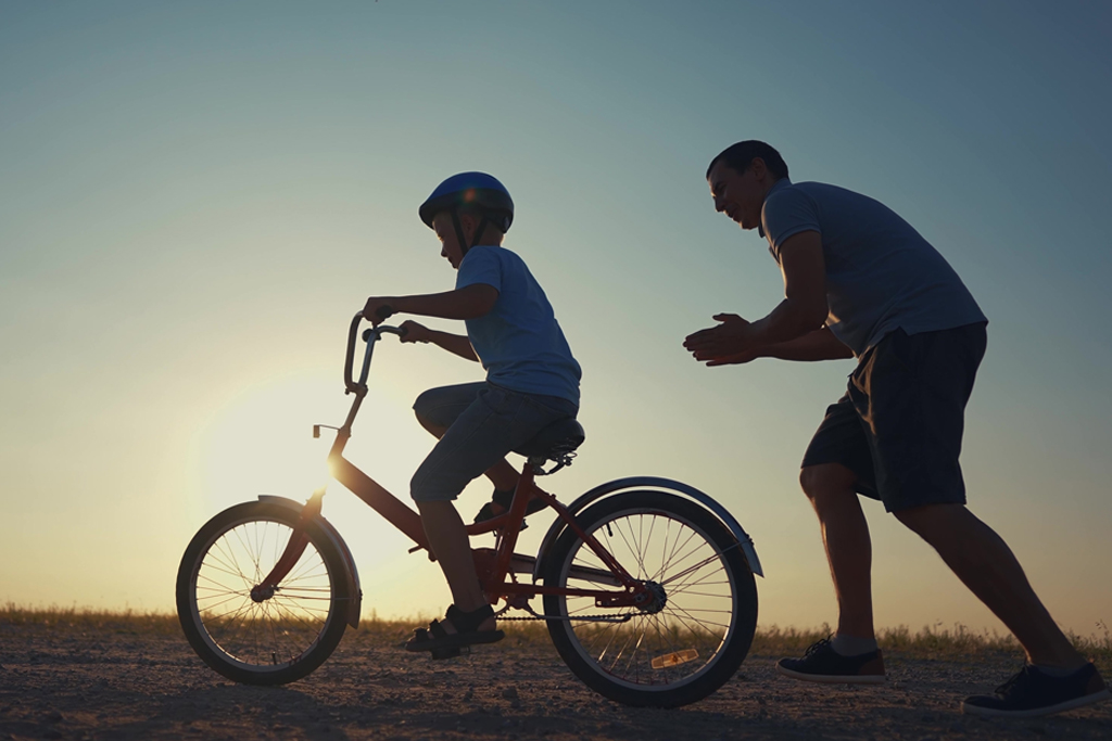 Father encouraging son learning to ride a bike