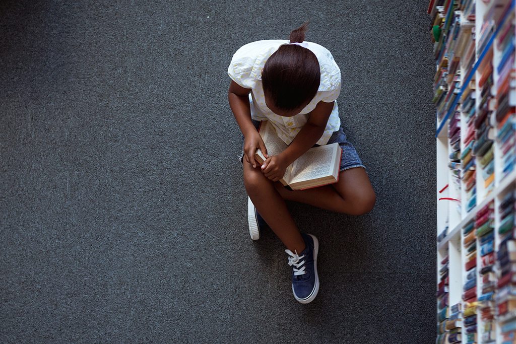 Child reading a book on the library
